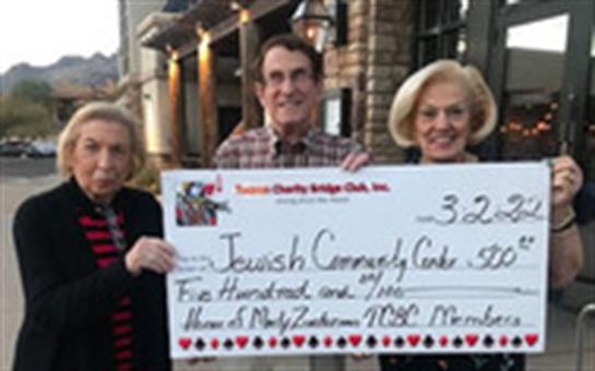 Two women and a man proudly present a large check to support the local Jewish Community Center.