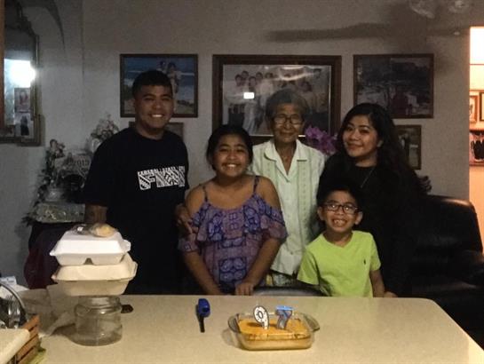 Five family members gather in a warm living room, enjoying each other's company.