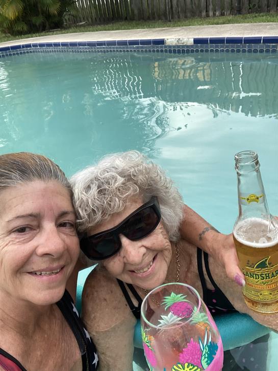 Friends relaxing by a pool, sharing drinks and smiles under the bright sunshine.