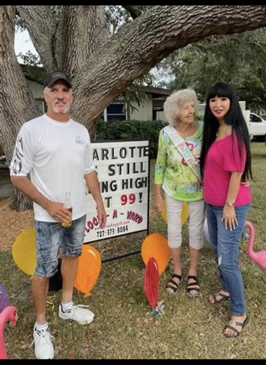 Three people gather by a decorated sign celebrating Charlotte's milestone with vibrant decorations.