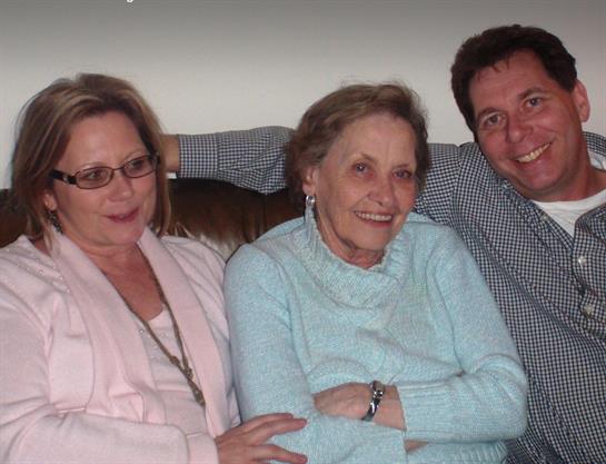 Three family members relax on a couch, sharing joyful moments during a family gathering.