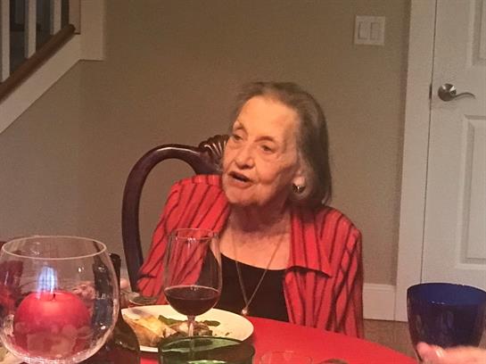 Older woman passionately engages in conversation while dining with family members.