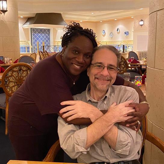 A happy couple shares a loving embrace in a restaurant, showcasing their connection.