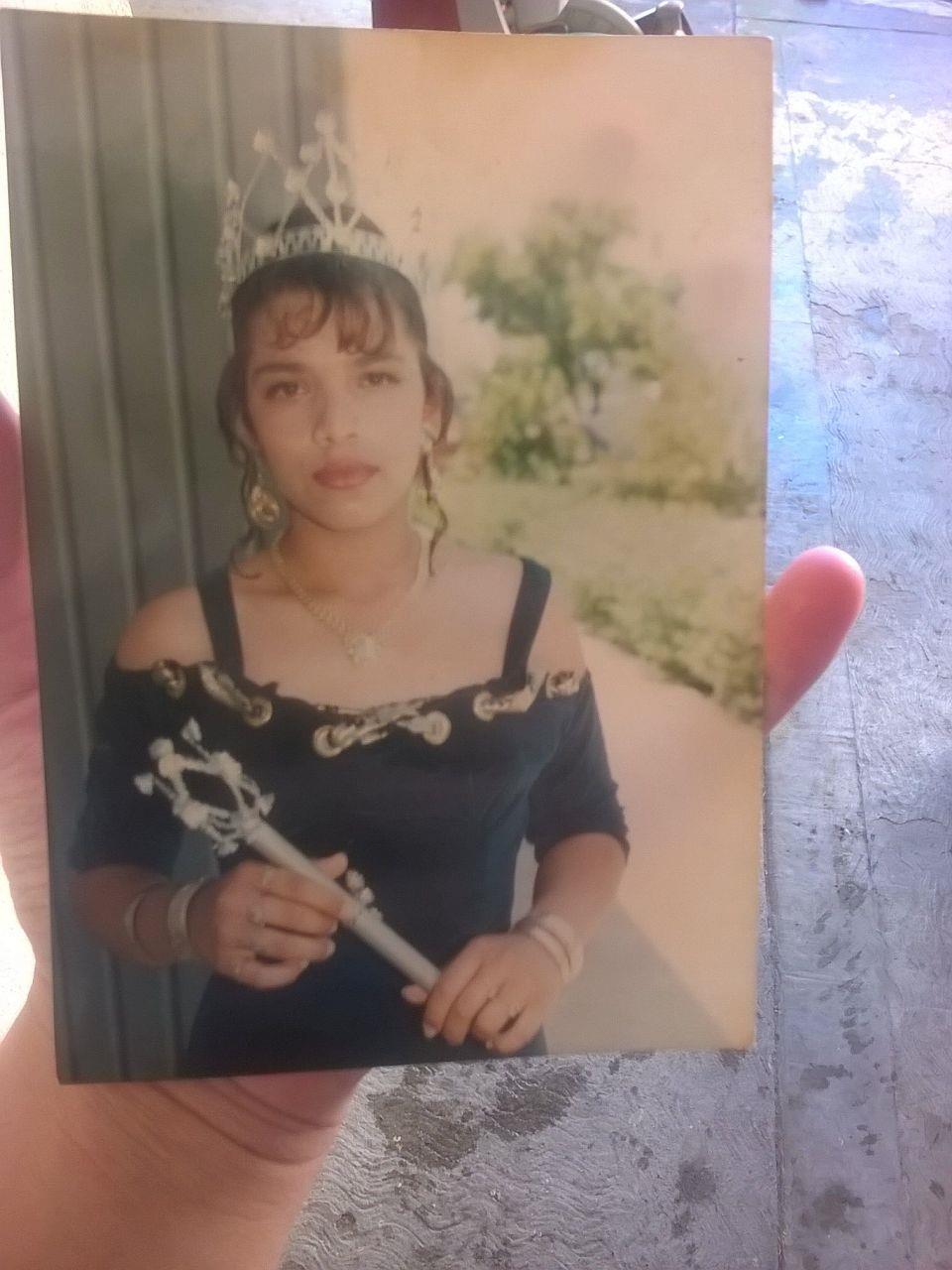 A hand holding a photograph of a woman