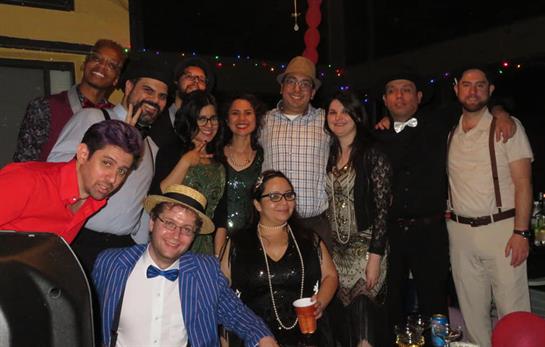 Friends gather together at a lively indoor party, showcasing diverse outfits and joyful smiles.