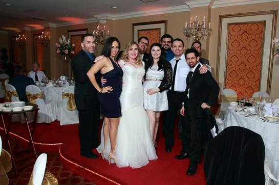 Friends in formal attire smile and celebrate together in a banquet hall.