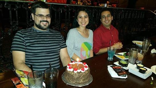 Three friends enjoying dessert together at a lively restaurant during the evening.