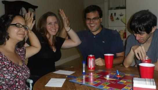 A group of friends is engaged in a fun game night, sharing drinks and laughter.