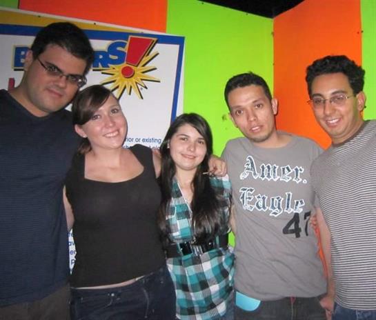 Five friends pose happily together in a colorful space, enjoying each other's company.
