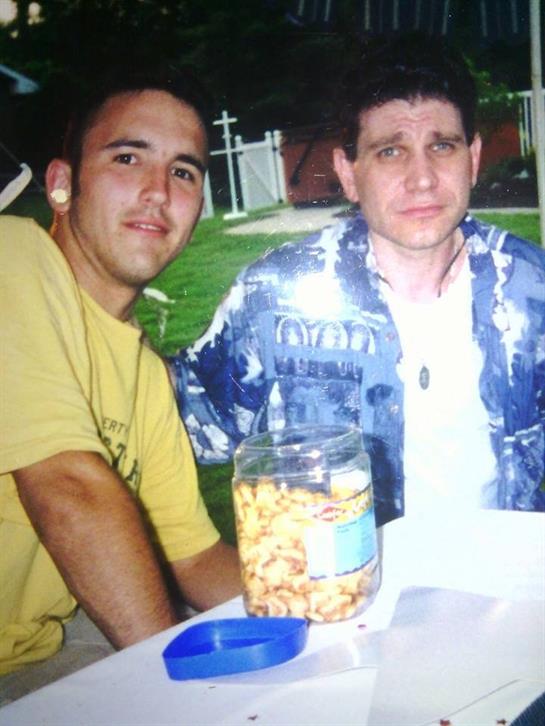 Two men sitting at a table with a jar of popcorn