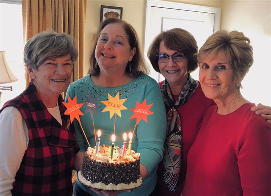 A group of women holding a cake with candles
