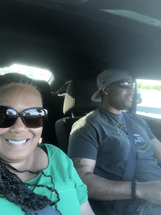 Two people are happily driving in a car, wearing sunglasses and enjoying their time together.