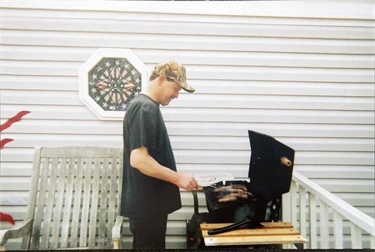 A man standing outside grilling meat