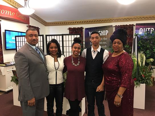 Group of five individuals posing together in a community center, highlighting unity and joy.