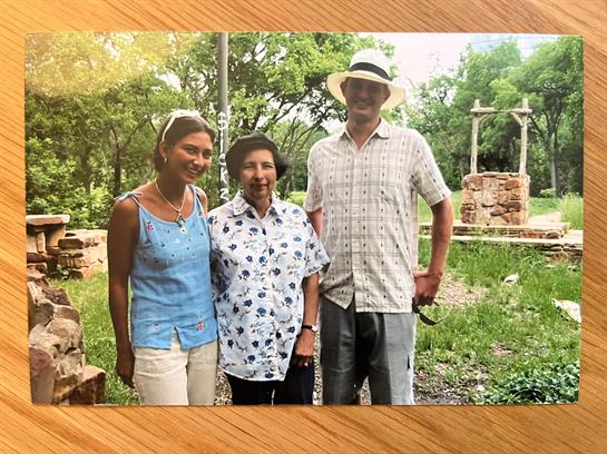 Three individuals pose together in a lush green area filled with historical ruins.