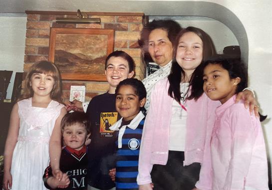 Kids and an adult share smiles while posing for a fun group picture in a warm environment.