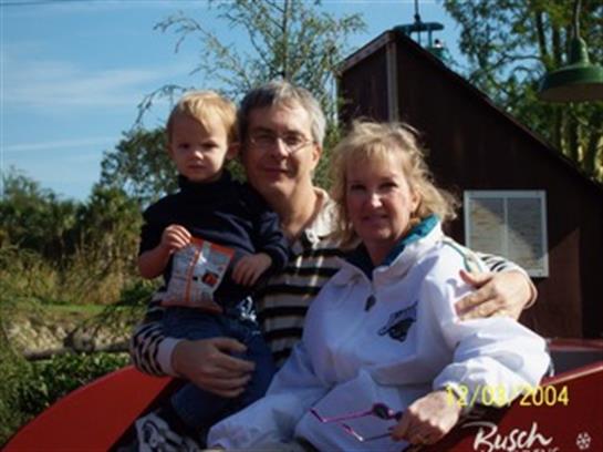 A family of three poses together outdoors, showing smiles and snacks during a joyful outing.