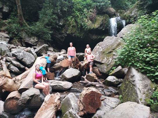 A group of people standing on rocks near a waterfall