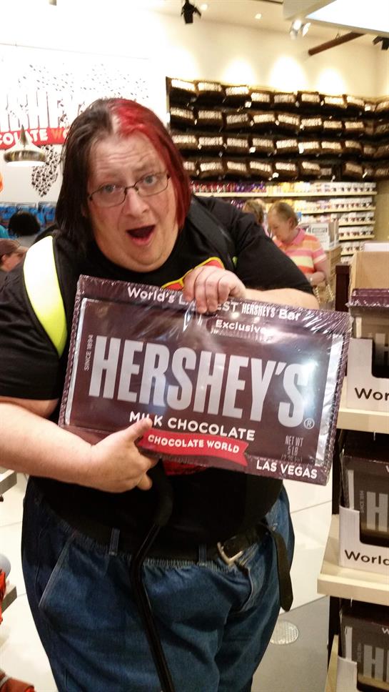 A person excitedly holds a large chocolate bar while shopping in Las Vegas, surrounded by treats.