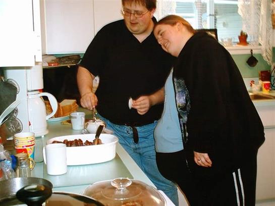 A couple prepares a meal together, sharing joyful moments in a cheerful kitchen.