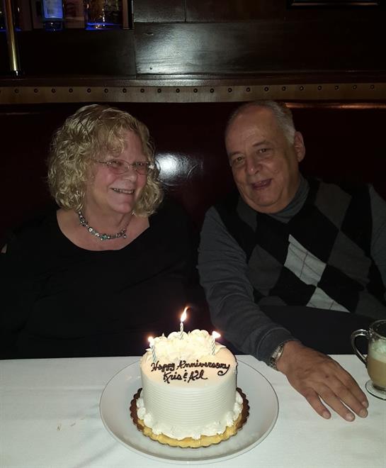 A man and woman sitting at a table with a cake
