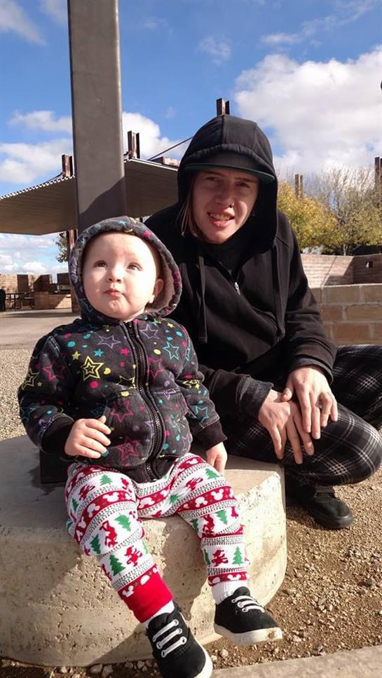 Adult and child enjoy a sunny day at the park, wearing cozy outfits and smiling happily.