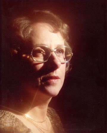 A woman wearing glasses and a gold necklace