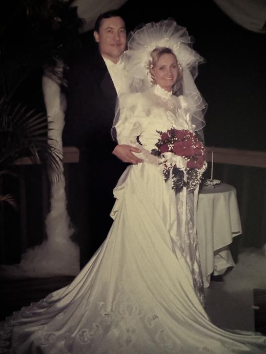 Bride and groom stand together, smiling joyfully while holding a bouquet amidst serene decor.