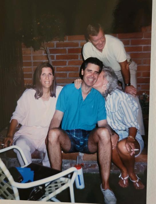 Four family members share joy and affection in a cozy backyard.