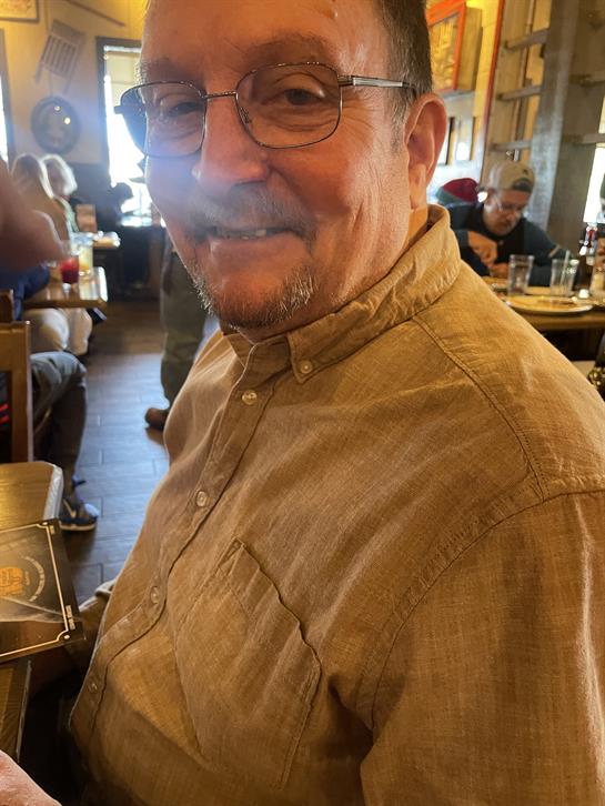 A man wearing glasses and a brown shirt