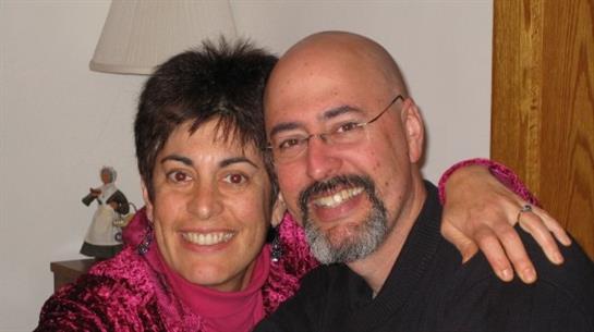 Two individuals share a joyful moment together indoors, surrounded by warm decor and light.
