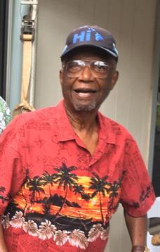 A cheerful elderly man in a bright shirt enjoys a lively outdoor gathering with friends.