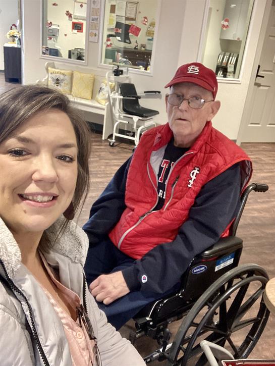 Caregiver and elderly man share a joyful moment in a center, capturing a memorable selfie together.