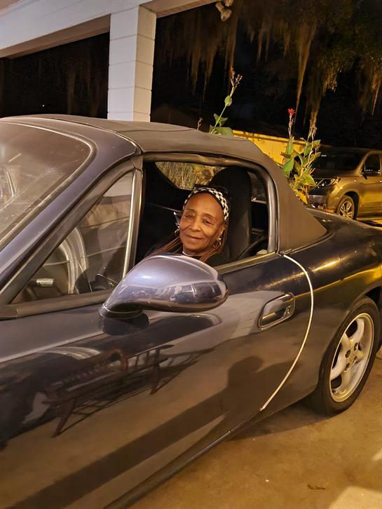 A woman sits in a convertible car at night, taking in the evening atmosphere while parked.