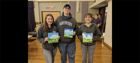 A group of people holding paintings