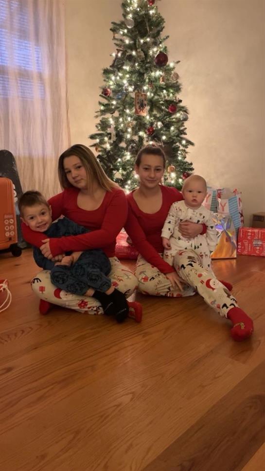 A group of people sitting on the floor in front of a christmas tree