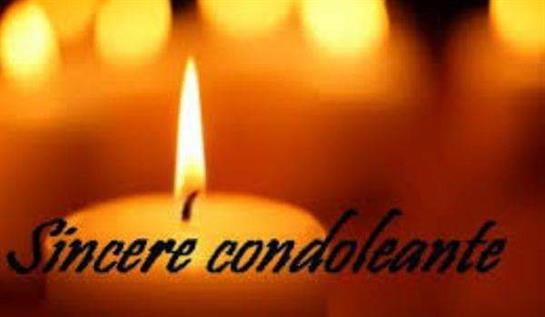 A lit candle illuminates a soft glow while a message of condolences is conveyed nearby.