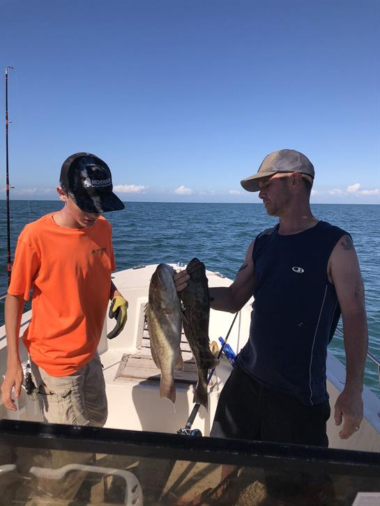 Two fishermen show off their successful catch while enjoying a day out on the water.