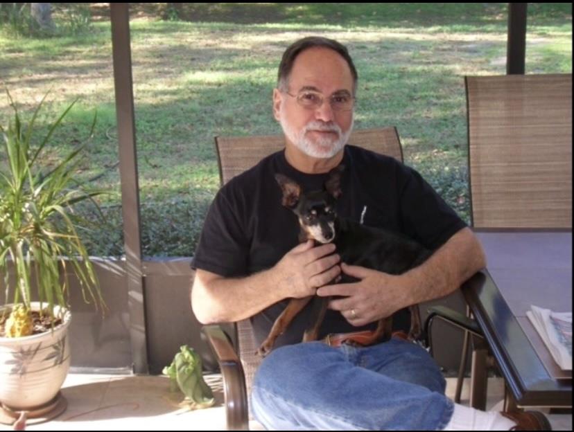 A man enjoys quality time with his small dog in a peaceful outdoor area on a sunny day.