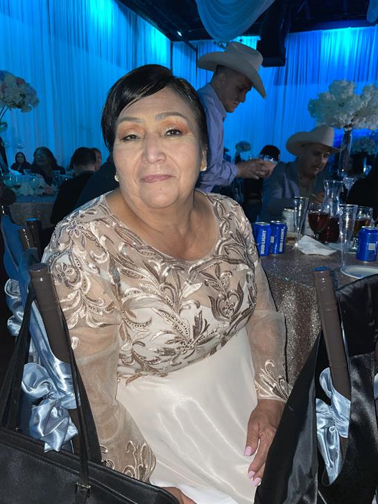 A woman dressed in a beautifully adorned gown sits gracefully at a table during a celebration.