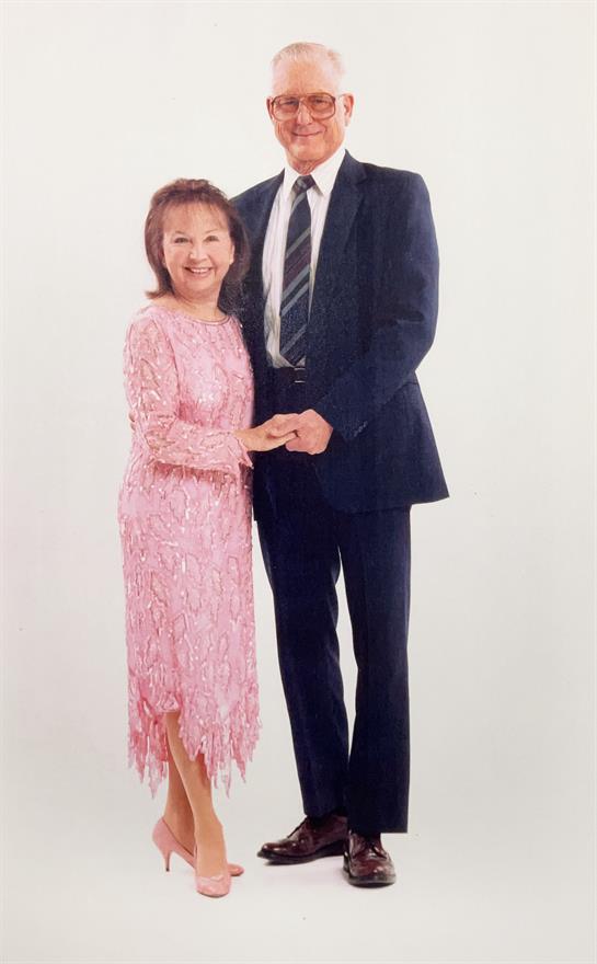 Couple dressed formally smiles while holding hands, radiating joy at their special event.