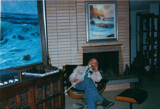 A musician sits comfortably in an armchair, enjoying a moment of relaxation in a warm living room.
