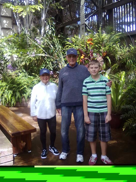 Three family members enjoy a visit to a tropical greenhouse surrounded by vibrant greenery.