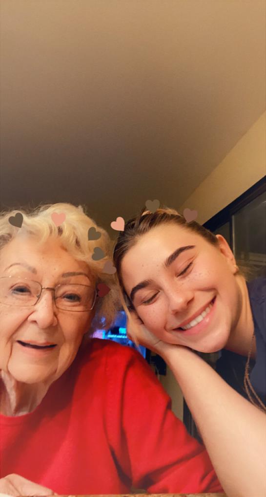 A young woman smiles with an elderly woman, both enjoying a heartfelt moment together.