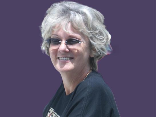 A woman with curly hair enjoys an uplifting moment, looking directly at the viewer with a smile.