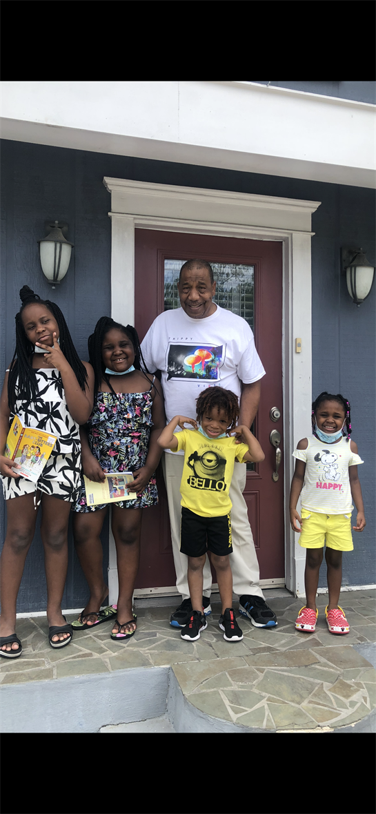 Five smiling kids pose with their grandfather at the entrance of a blue house.