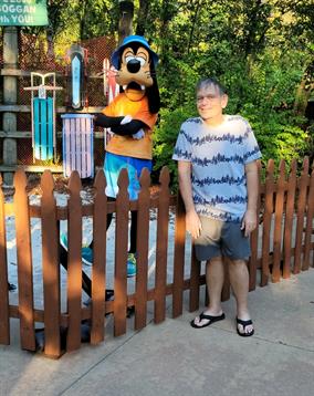 A person enjoys time next to a character in costume at a fun outdoor location.