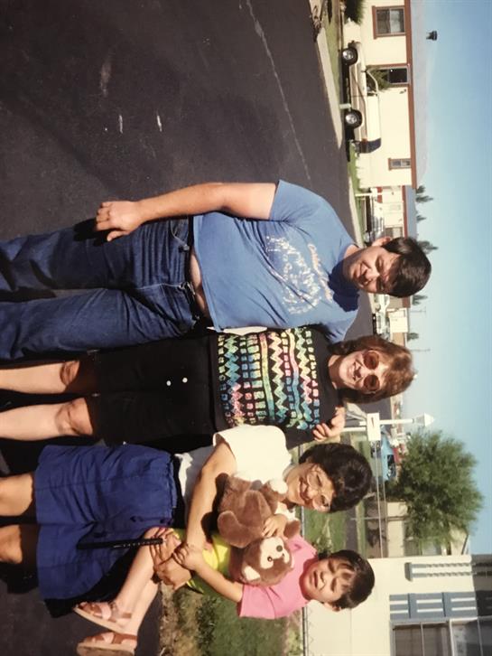 A cheerful family stands together outside their home, enjoying quality time on a sunny day.