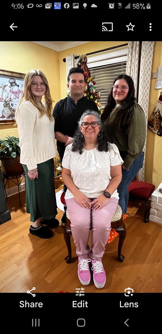 Four family members pose together in a festive living room beside a Christmas tree.