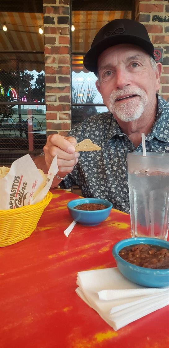 A man savoring chips at a lively restaurant with bright decor and tasty dishes.